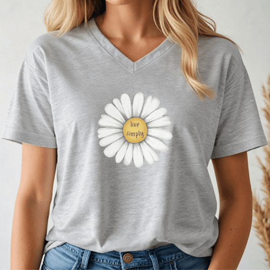 Person wearing a gray v-neck t-shirt with a white daisy graphic and 'live simply' text.