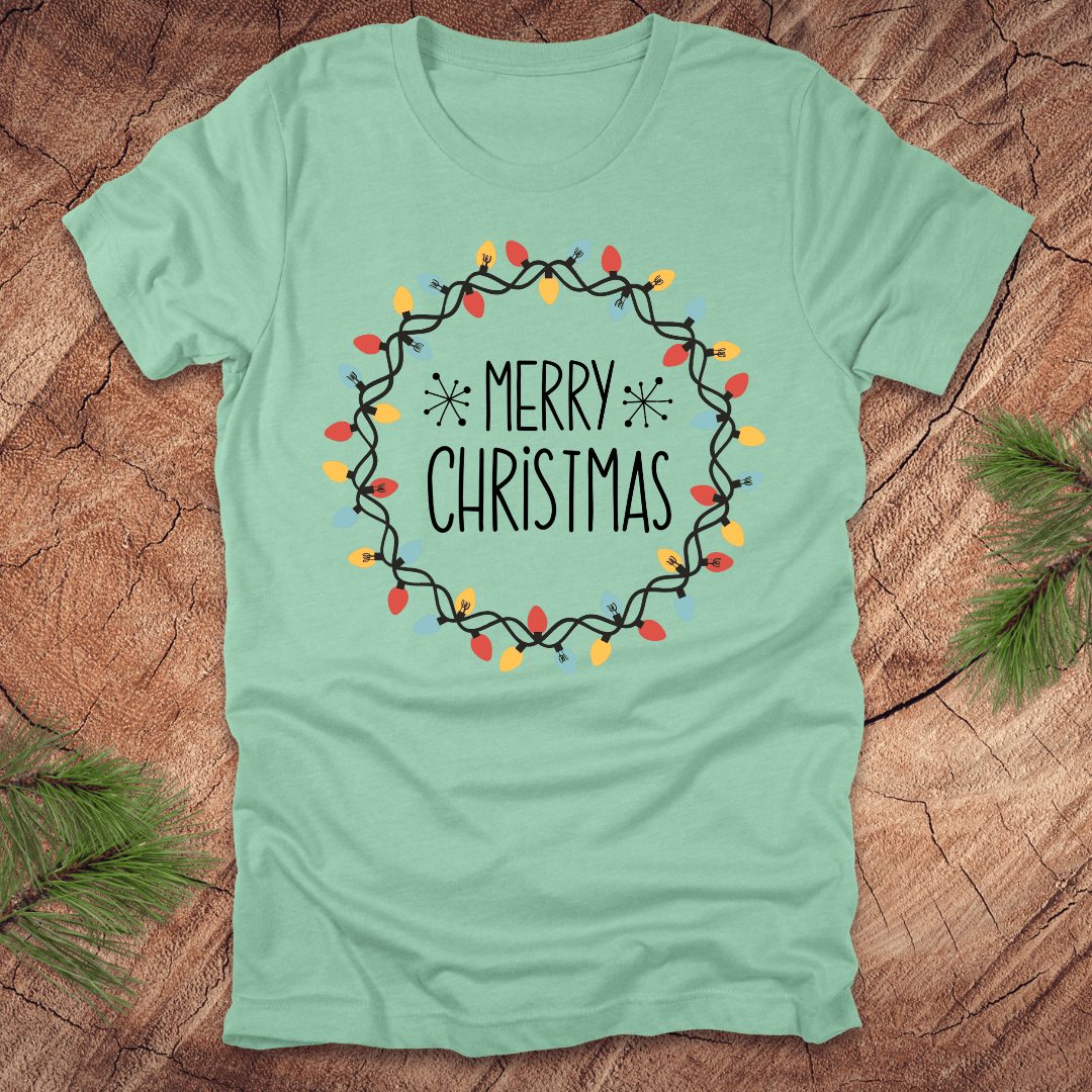 Mint green t-shirt with 'Merry Christmas' design on a wooden surface