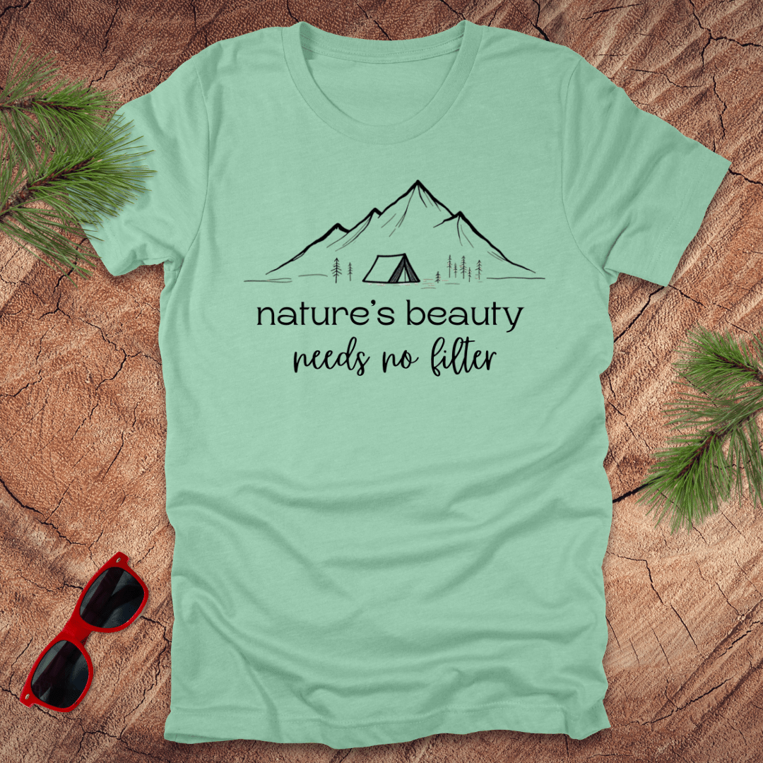 Mint green tshirt with mountains and tent graphic with text, 'nature's beauty needs no filter' on a wood background.