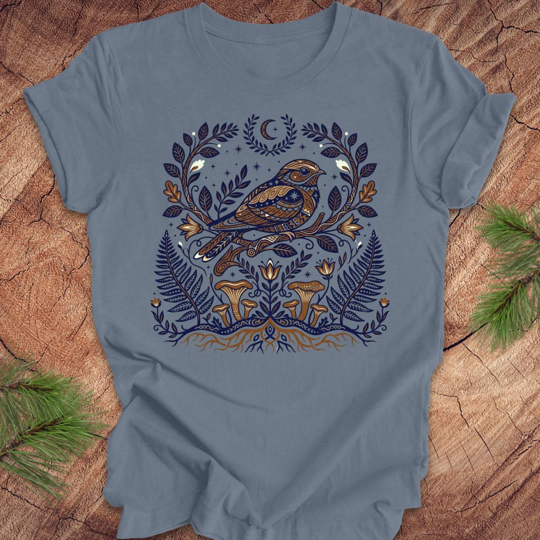 Blue t-shirt with a whip-poor-will and nature-themed design on a wooden surface.