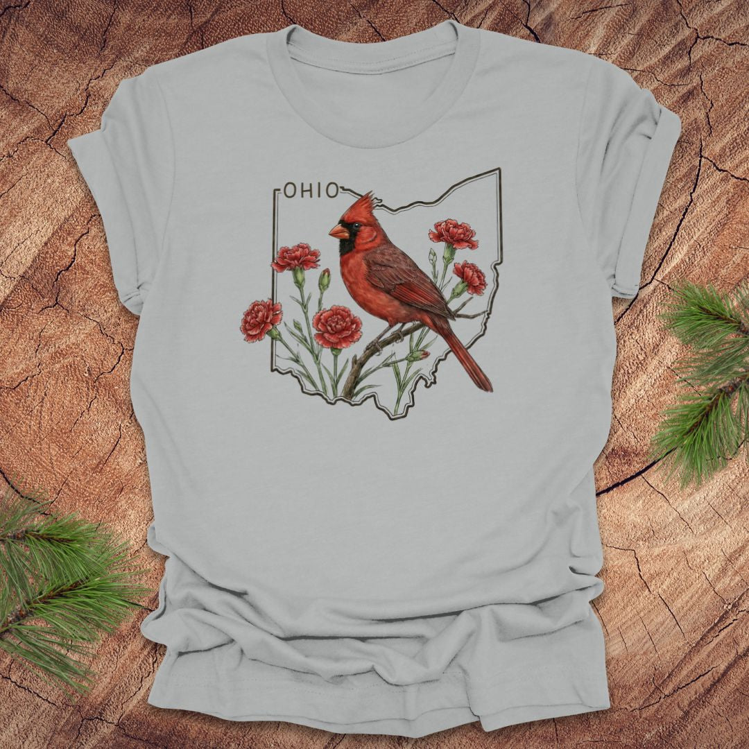 Silver t-shirt with a cardinal and floral design on an Ohio map, placed on a wooden surface.