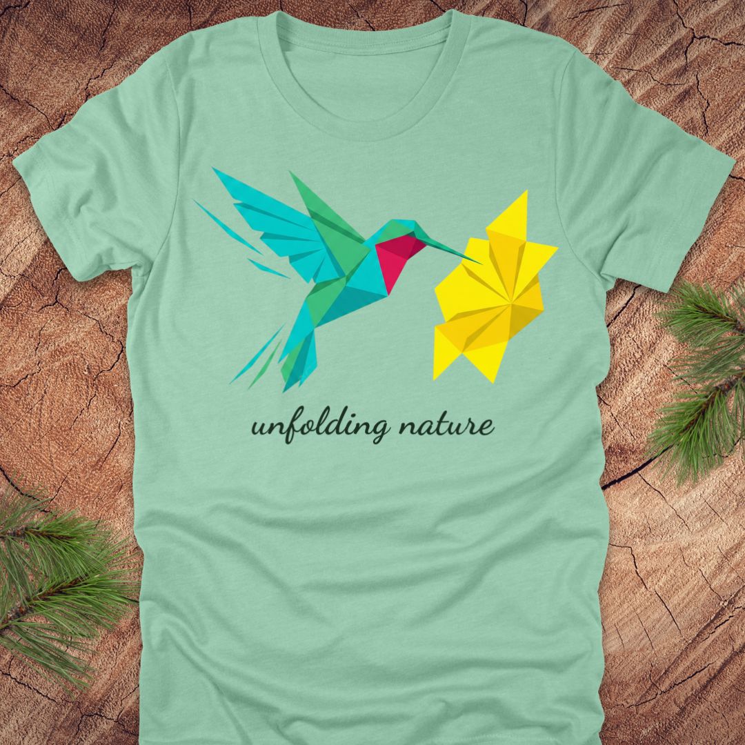Light green t-shirt with a colorful hummingbird and flower design on a wooden surface.