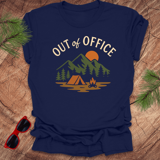 Navy blue t-shirt with 'Out of Office' graphic design on a wooden surface with sunglasses and pine branches.