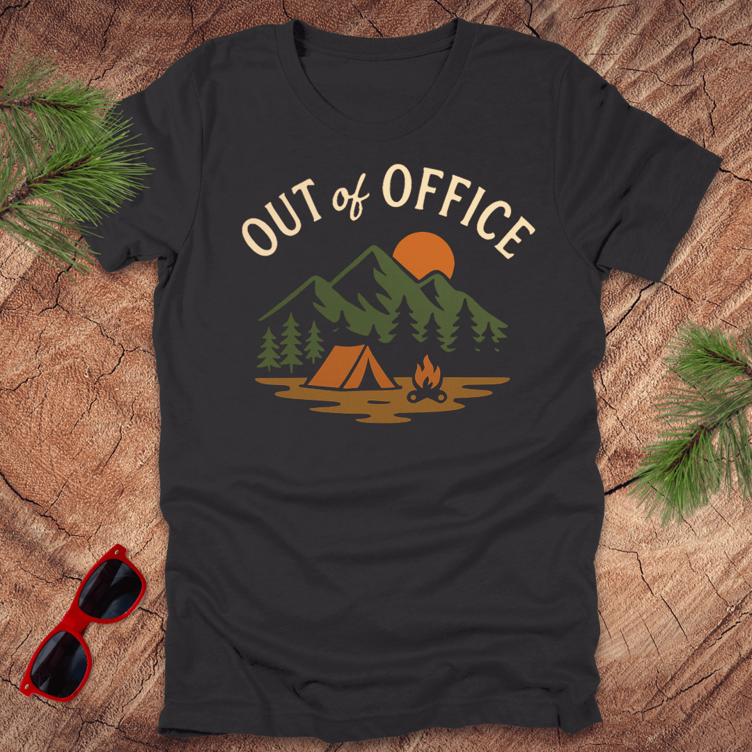 Dark gray t-shirt with a graphic print featuring a tent, trees, and mountains, and the text 'OUT OF OFFICE' on the front, accompanied by a pair of sunglasses and pine branches in the background.