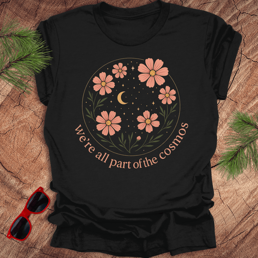 Black t-shirt with floral design and text on a wooden surface with sunglasses and greenery.