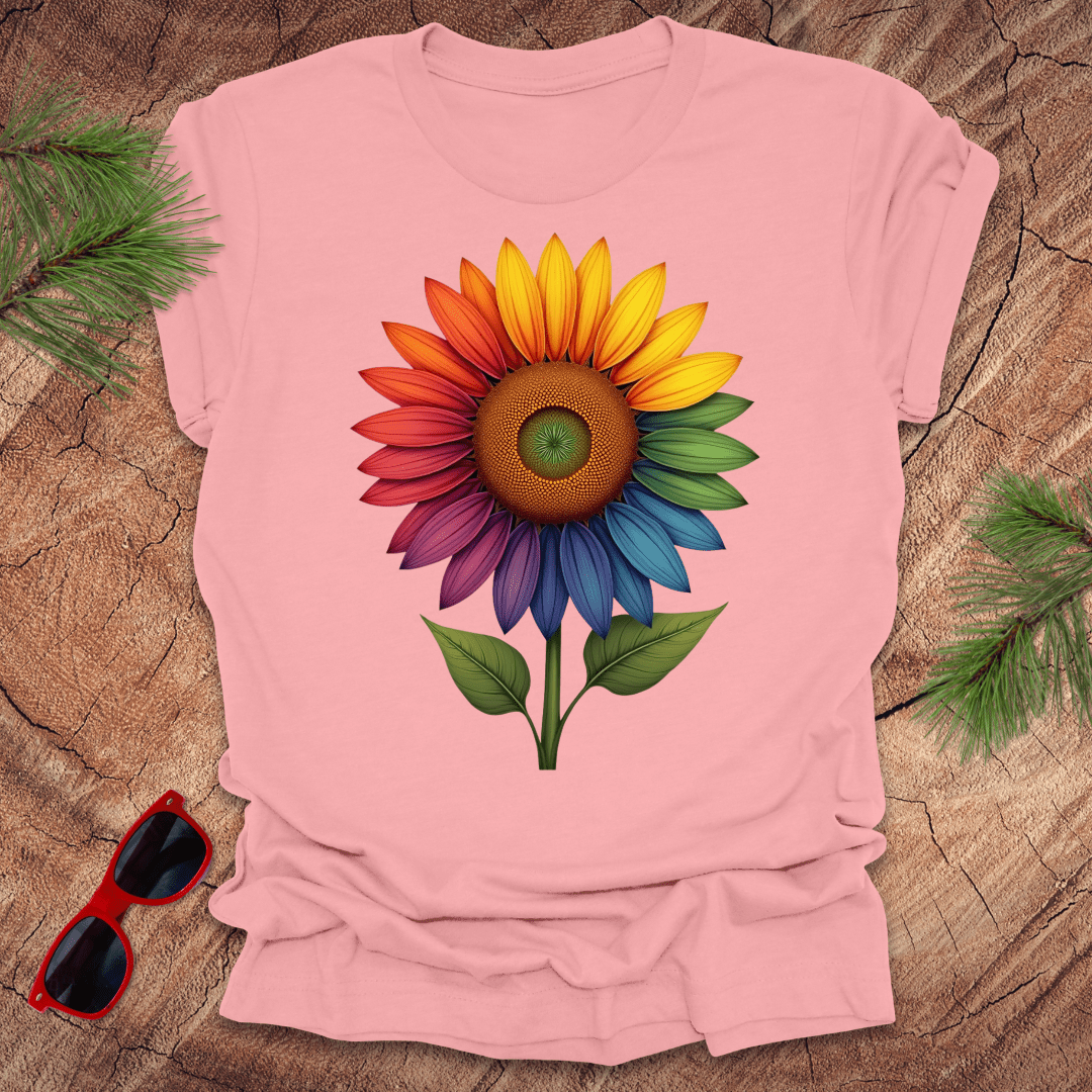 Pink tshirt with a bold rainbow sunflower graphic on a wood background.