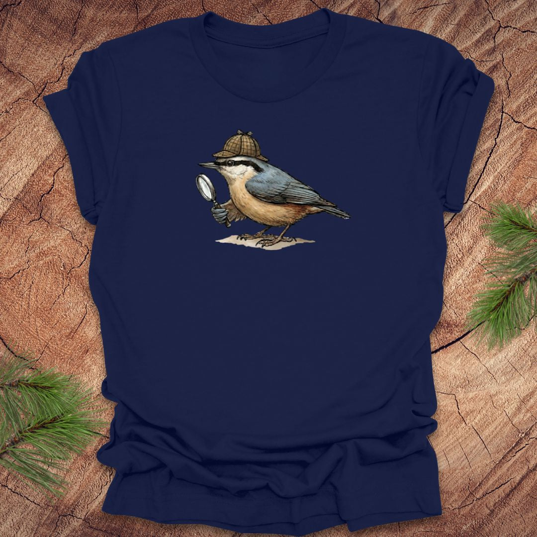 Navy blue t-shirt with a nuthatch bird wearing a sherlock holmes cap and holding a magnifying glass on a wooden surface