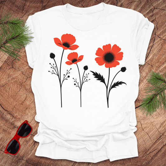 White t-shirt with red floral design on a wooden surface with sunglasses and greenery.