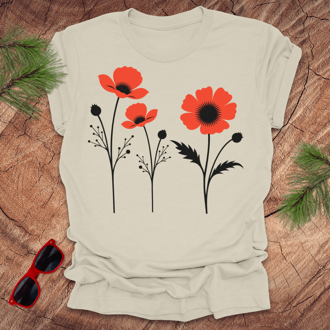 Beige t-shirt with red floral design on a wooden surface with sunglasses and greenery.