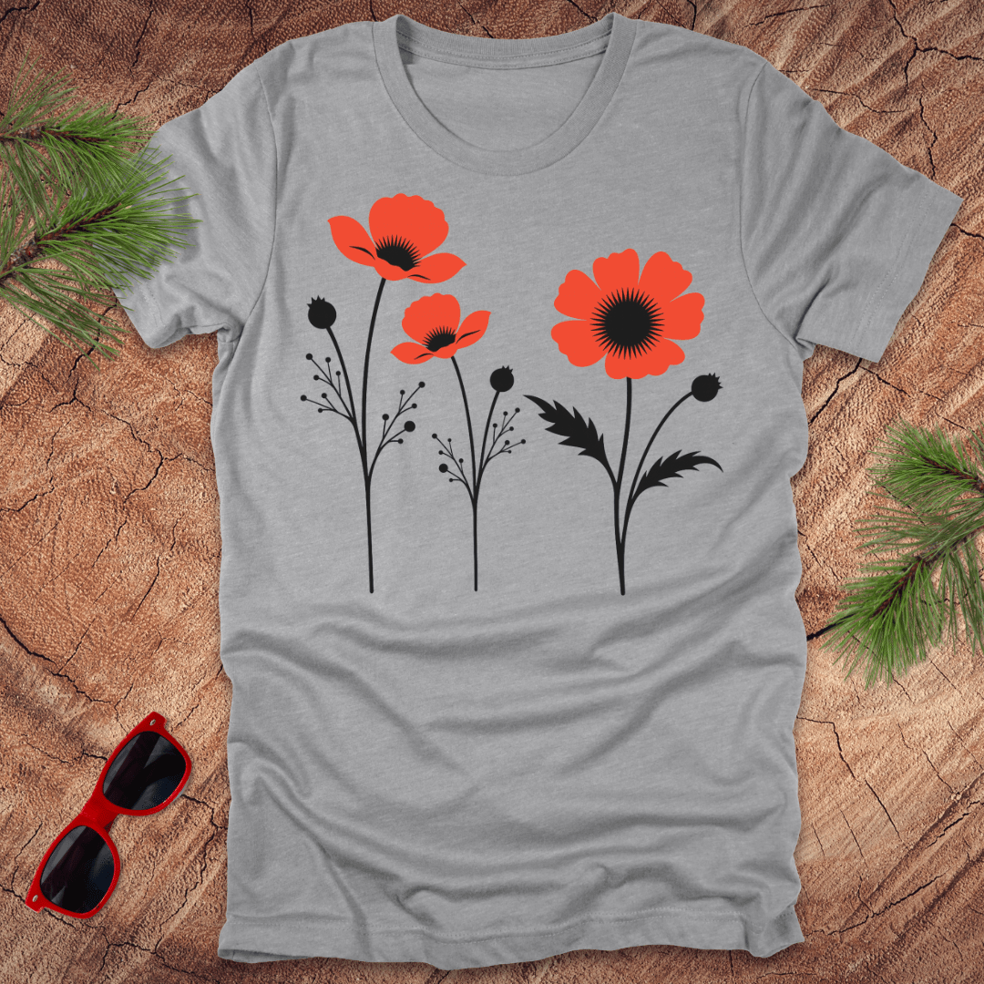 Gray t-shirt with red and black floral design on a wooden surface with sunglasses and greenery.