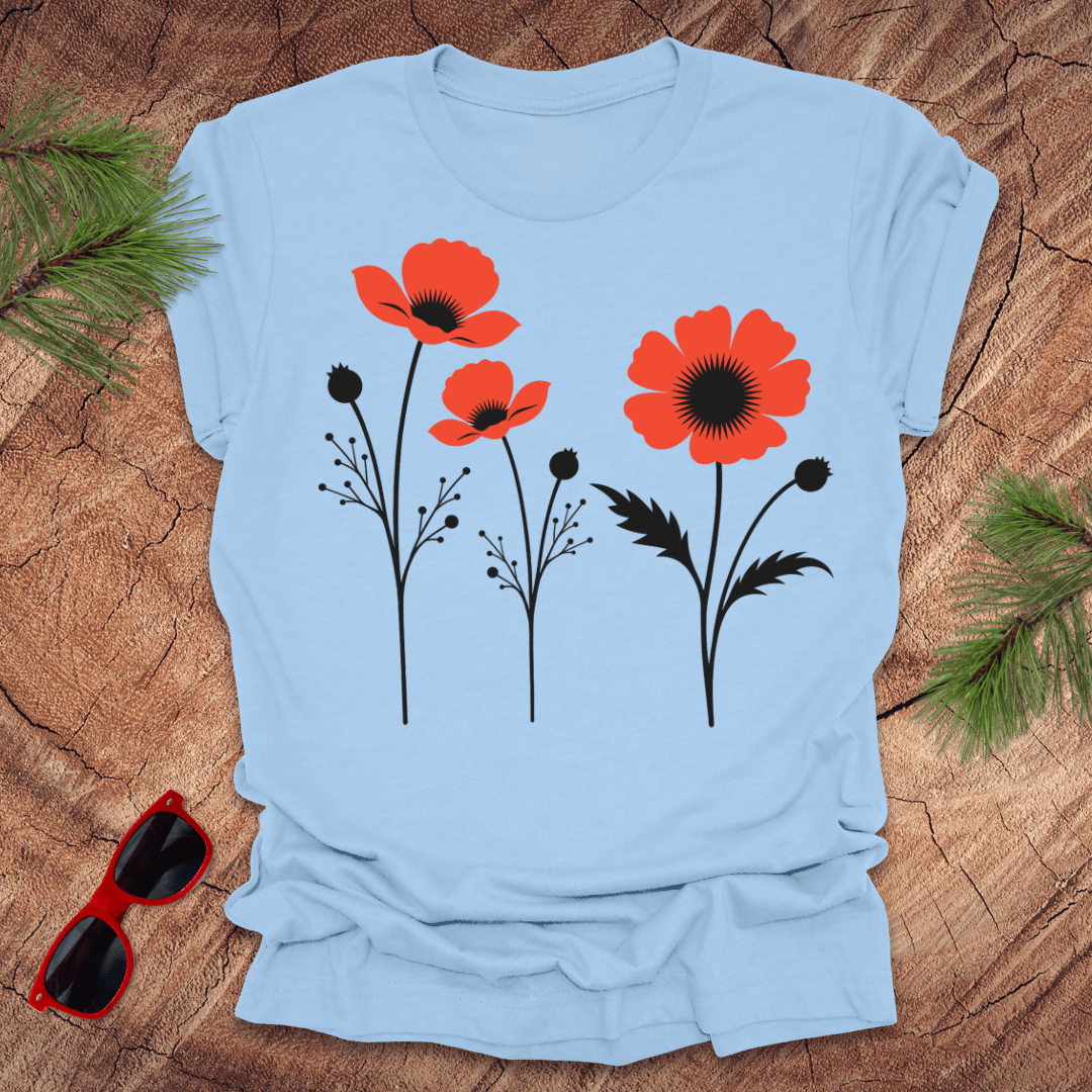 baby blue t-shirt with red floral design on a wooden surface with sunglasses and greenery.