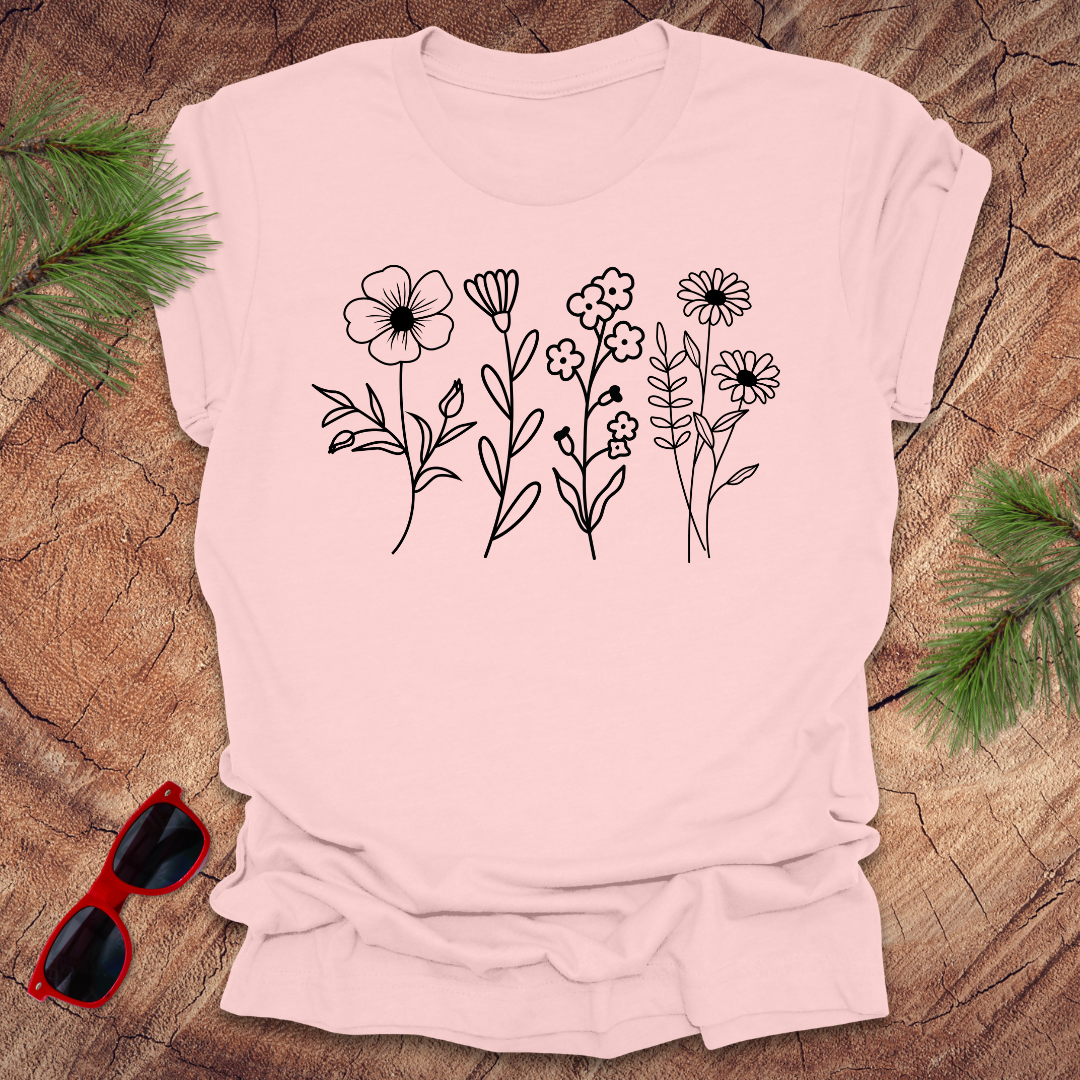 Pink t-shirt with floral design on a wooden surface with sunglasses.