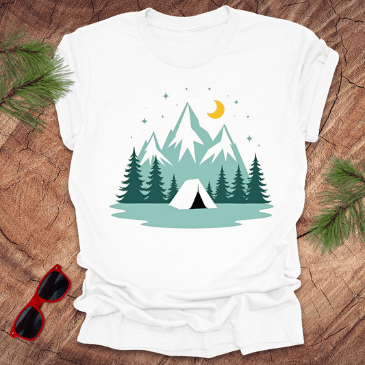 A white t-shirt with a graphic print of mountains, trees, a tent, moon, and stars.