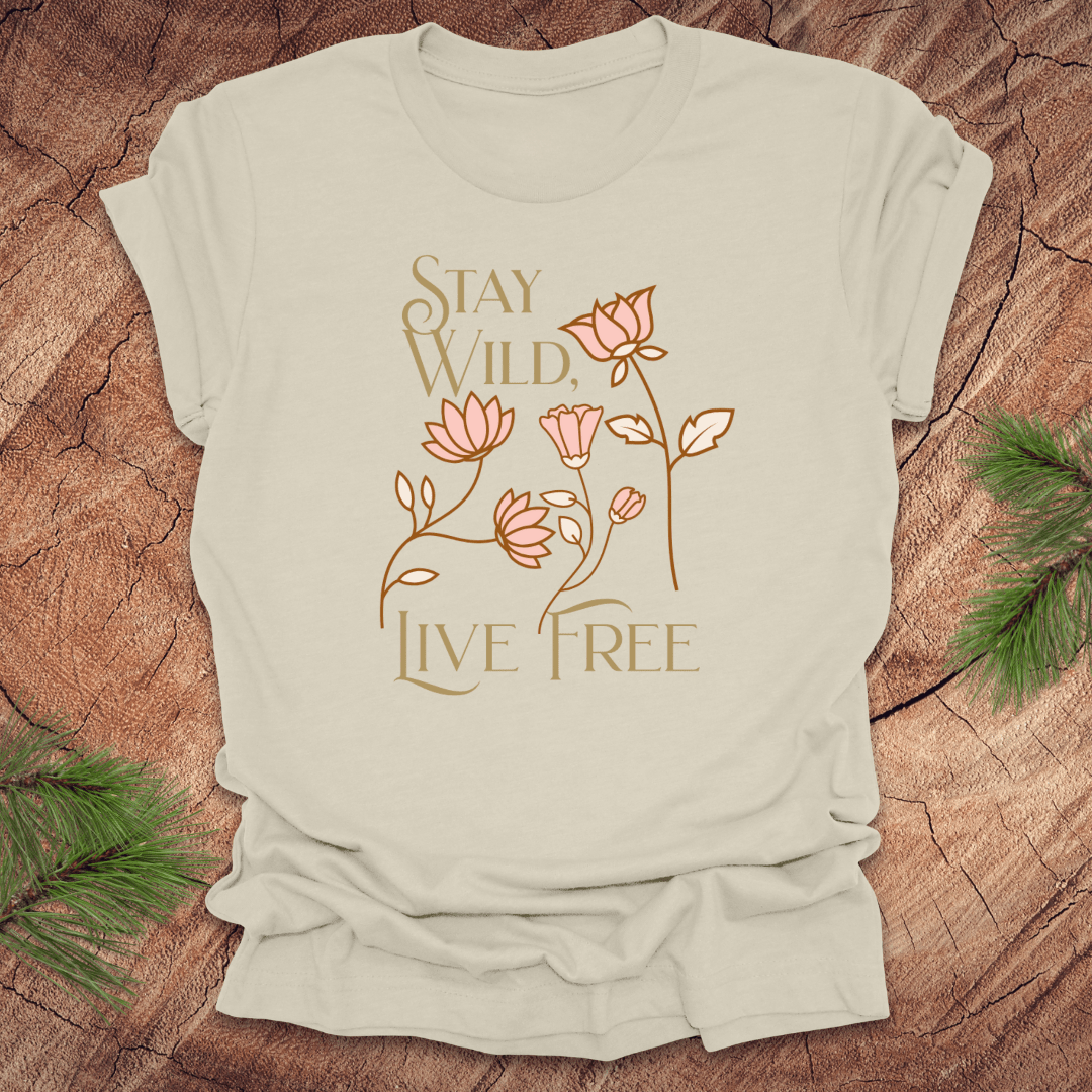 Beige t-shirt with 'Stay Wild, Live Free' text and floral design on a wooden surface.