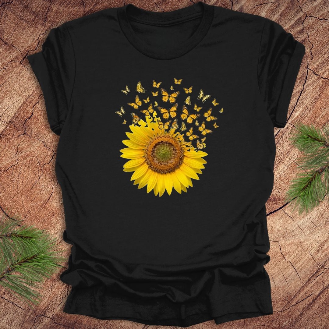 Black t-shirt with a yellow sunflower and butterflies design on a wooden surface.