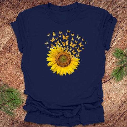 Navy blue t-shirt with a yellow sunflower and butterflies design on a wooden surface.