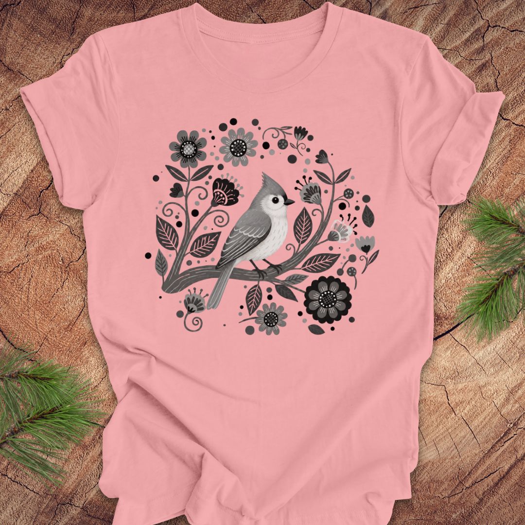Pink t-shirt with a titmouse bird and floral design on a wooden surface