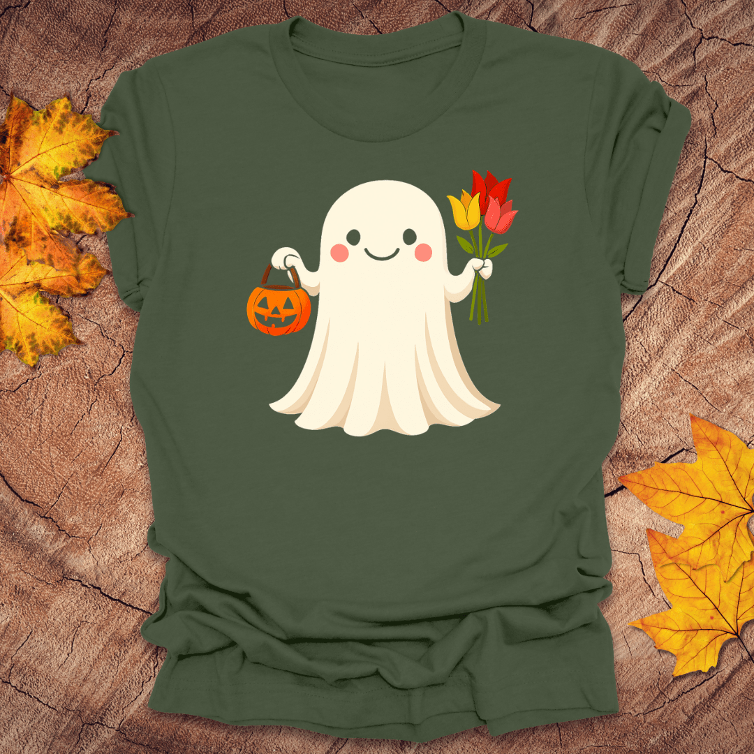 Green t-shirt with a ghost holding flowers and a pumpkin on a wooden surface with fall leaves.