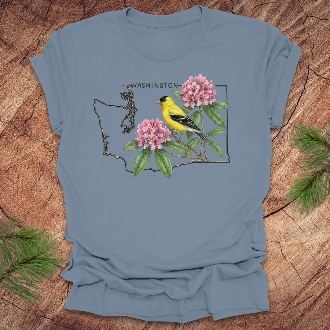 Steel blue t-shirt with Washington state outline with state bird goldfinch and rhododendron on a wood background.