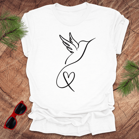 White t-shirt with hummingbird and heart design on a wooden surface with sunglasses and greenery.