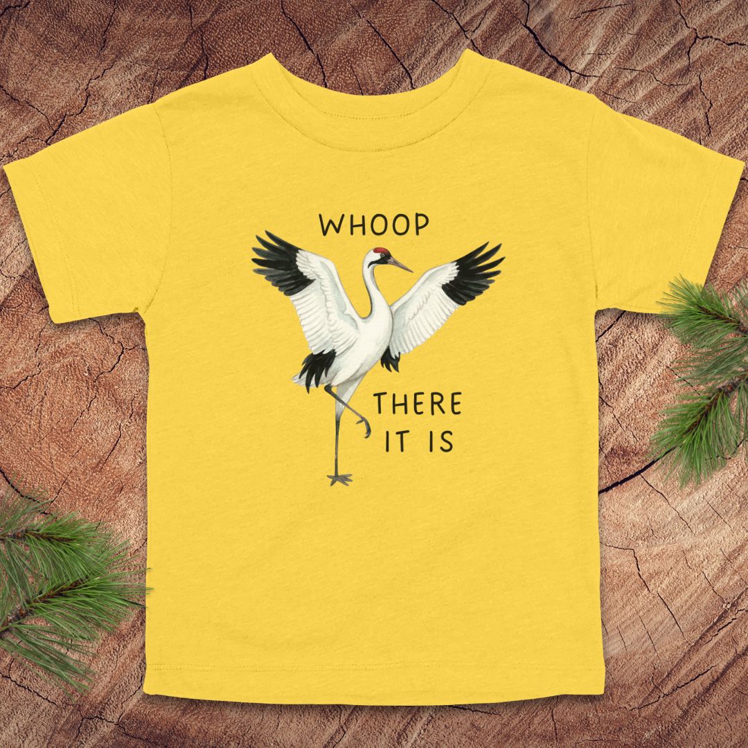 Yellow t-shirt with cranes and text on a wooden surface