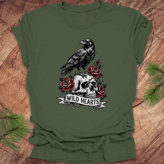 Green t-shirt with a crow, skull, and roses design with text, 'wild hearts' on a wooden surface.