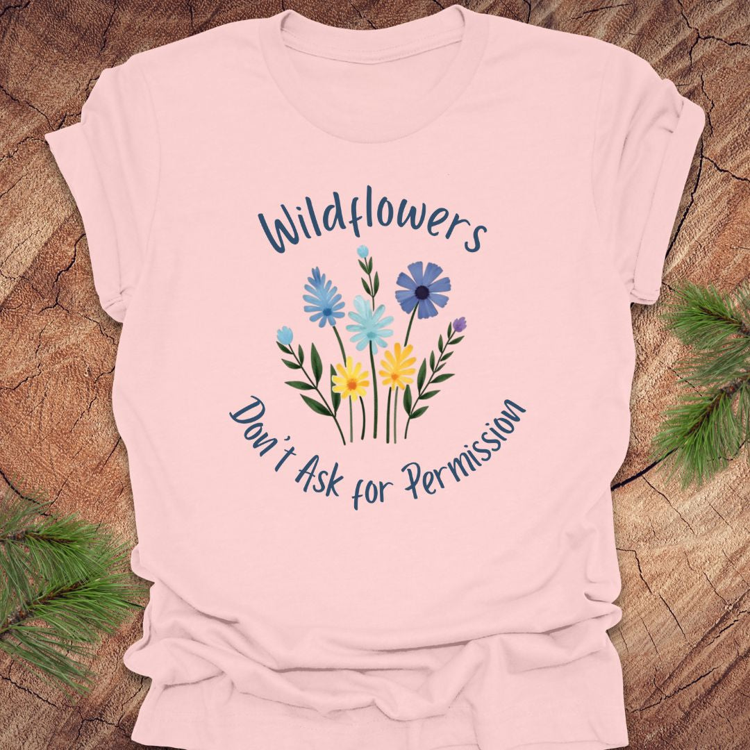Pink t-shirt with floral design and text on a wooden surface
