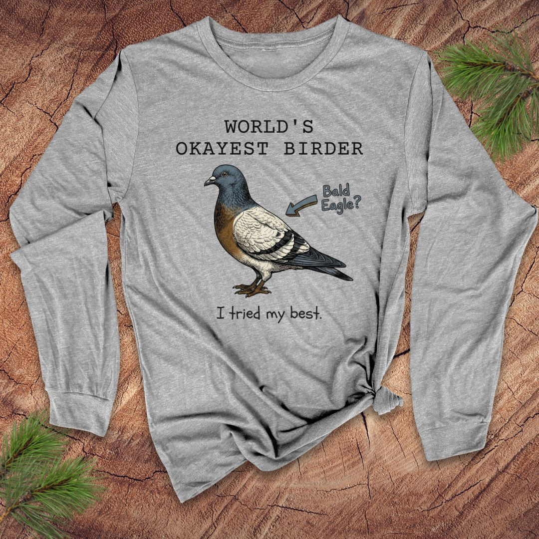 Gray long-sleeve shirt with a bird graphic and text, 'world's okayest birder' on a wooden surface