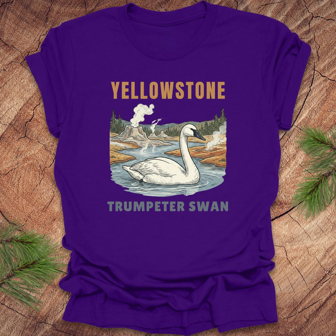 Purple t-shirt with Yellowstone and Trumpeter Swan design on a wooden surface