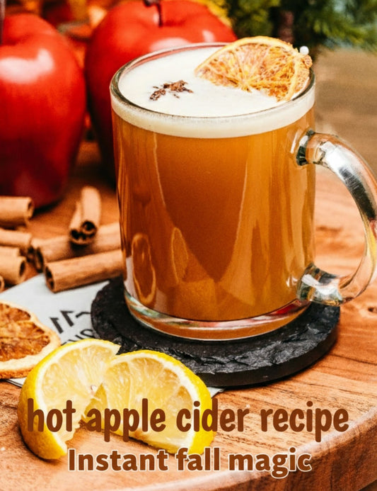 A glass of hot apple cider on a wooden table surrounded by lemons, apples and cinnamon sticks. the text reads "hot apple cider recipe. instant fall magic."