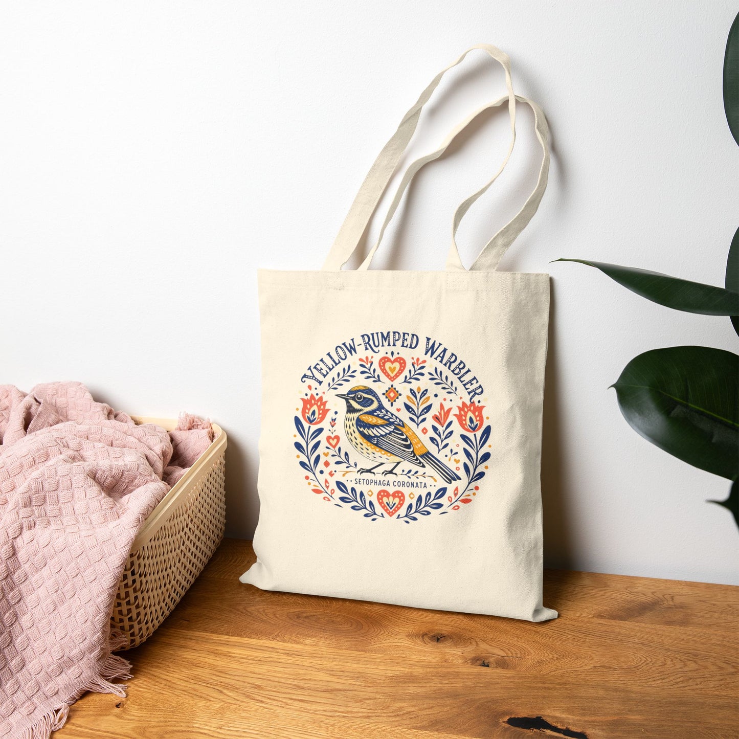 Canvas tote bag with a folk art yellow-rumped warbler design on a wood table.