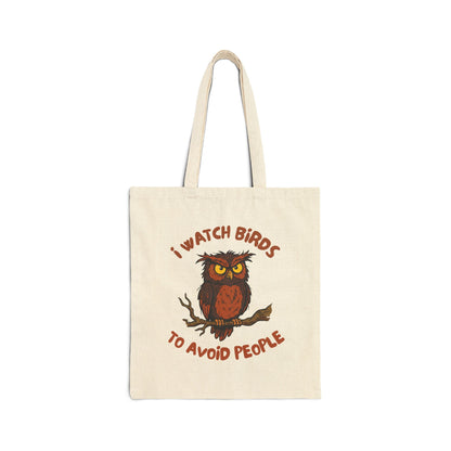 A canvas tote bag with owl design and text, 'i watch birds to avoid people' flat lay on a white background.