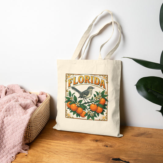 Tote bag with 'Florida' design featuring oranges and a mockingbird on a wooden surface.