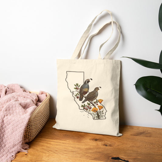 Tote bag with California bird design featuring birds and flowers on a wooden surface.