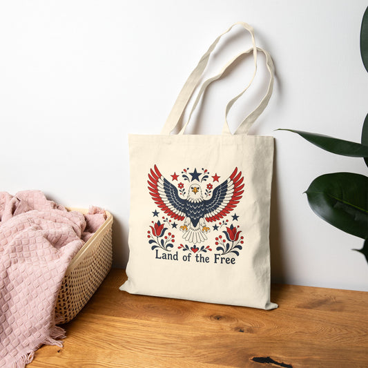 Tote bag with an eagle design and 'Land of the Free' text on a wooden surface.