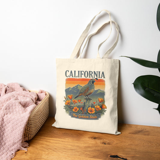 Tote bag with California design featuring a quail and flowers on a wooden surface.