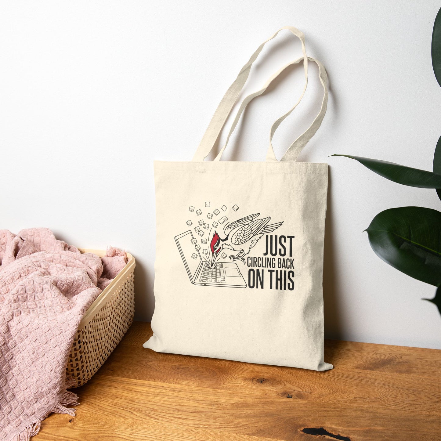 Tote bag with a woodpecker design and text on a wooden surface with a white wall background