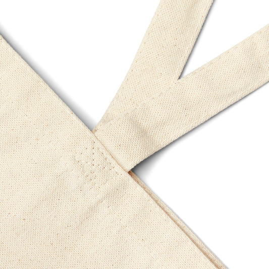 Close-up of beige canvas tote bag fabric with a cross pattern on a white background