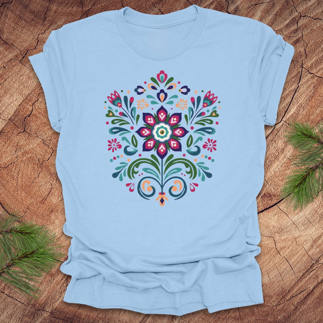 Baby blue t-shirt with a colorful dutch inspired floral design on a wood background.