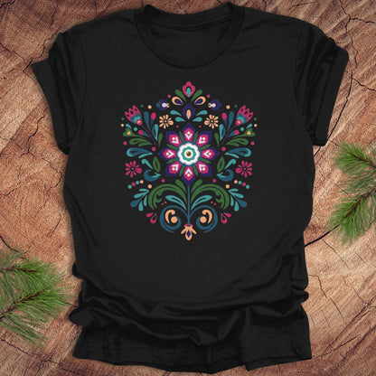 Black t-shirt with a colorful dutch inspired floral design on a wood background.