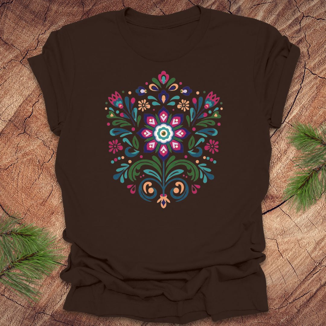 Brown t-shirt with a colorful dutch inspired floral design on a wood background.