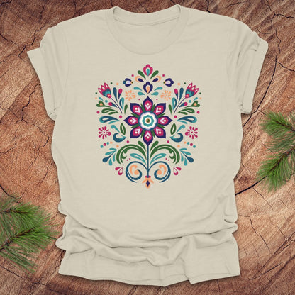 Beige t-shirt with a colorful dutch inspired floral design on a wood background.