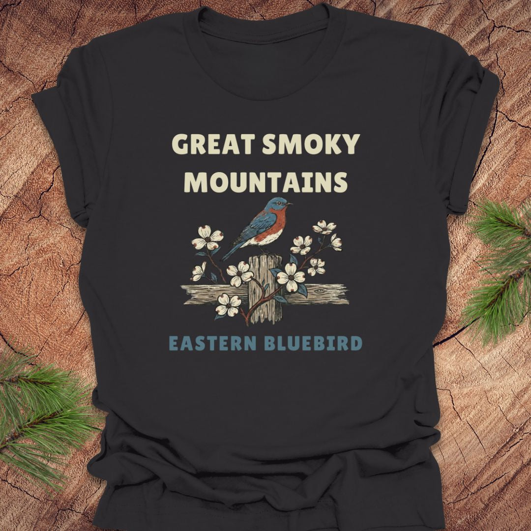 Black t-shirt with 'Great Smoky Mountains Eastern Bluebird' design on a wooden surface.