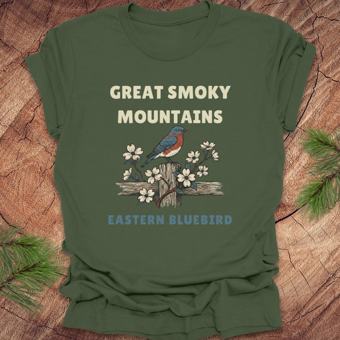 Green t-shirt with 'Great Smoky Mountains' and 'Eastern Bluebird' design on a wooden surface.