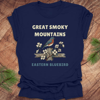 Navy blue t-shirt with 'Great Smoky Mountains' and 'Eastern Bluebird' design on a wooden surface.