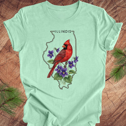 Mint green t-shirt with a red cardinal and purple flowers design on a wooden surface.