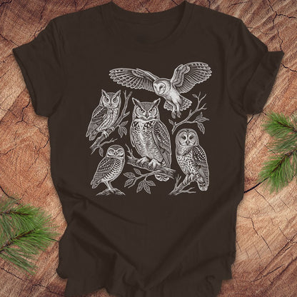 Brown t-shirt with white owl line-art illustrations on a wooden surface