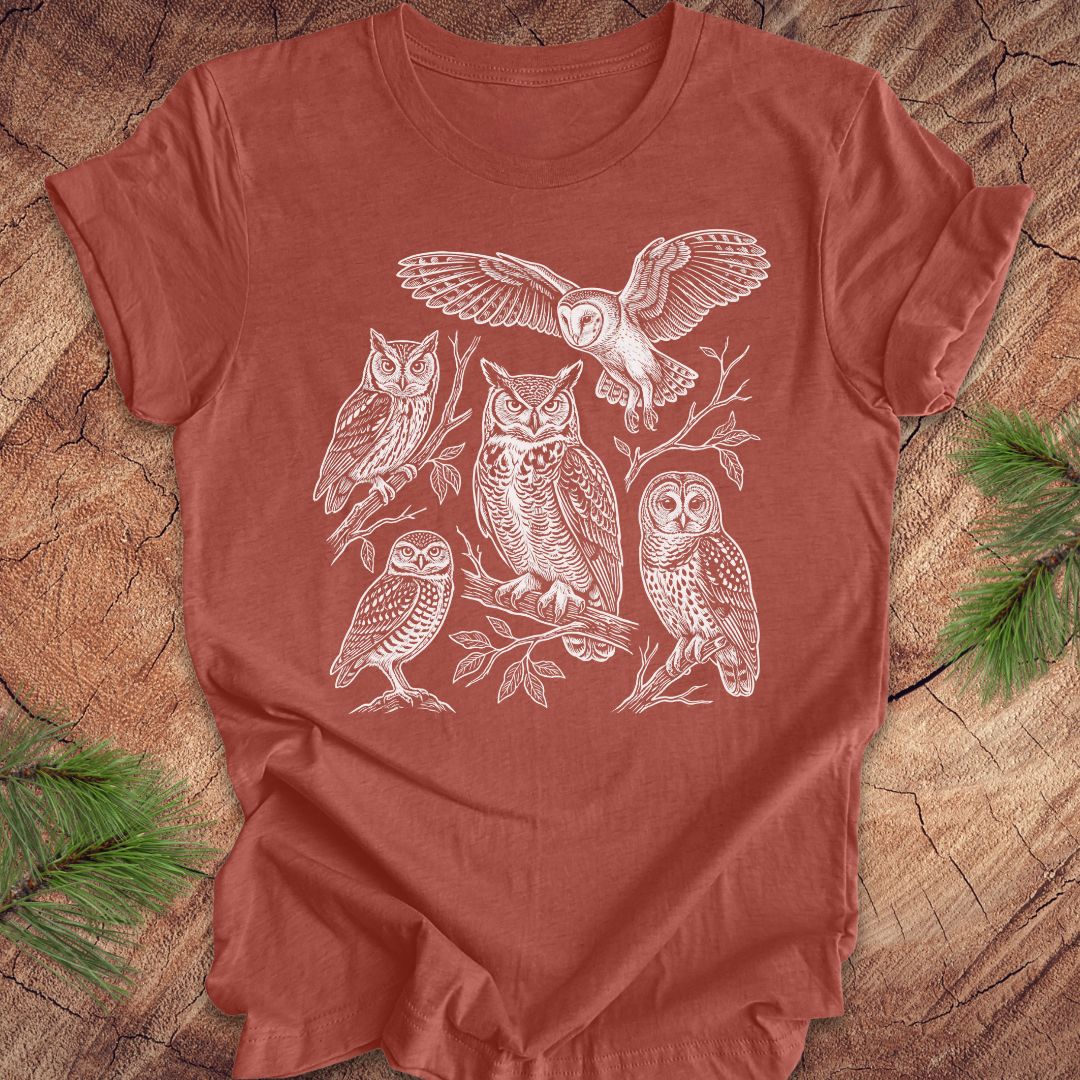Clay colored t-shirt with white owl line-art illustrations on a wooden surface