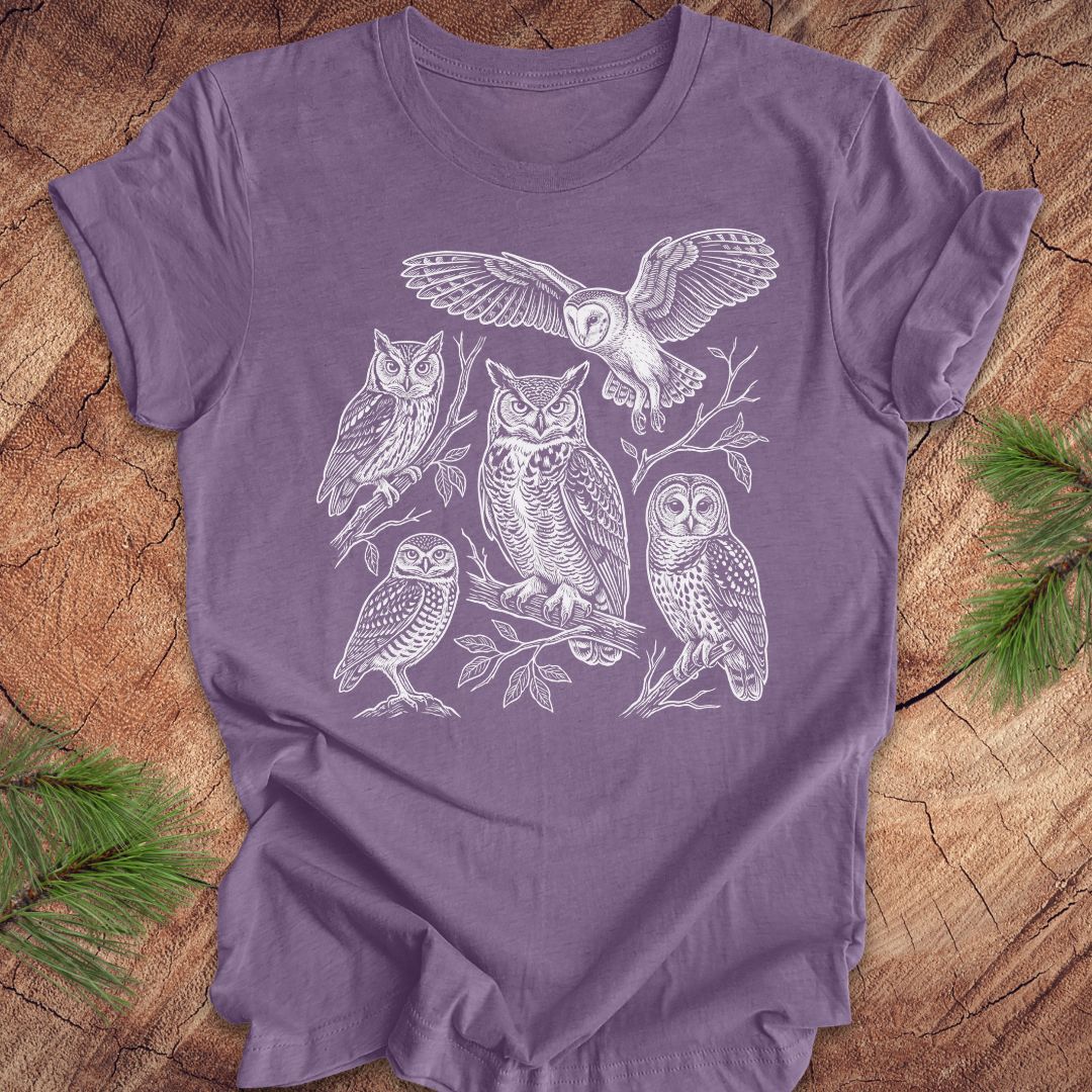 Purple t-shirt with white owl line-art illustrations on a wooden surface