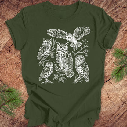 Green t-shirt with white owl line-art illustrations on a wooden surface